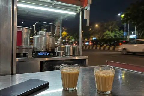 Two glasses of cutting chai and a phone at a Pune tea stall at night