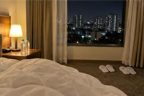 Hotel room window at night in Pune, two pairs of slippers by the bed