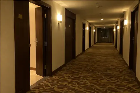 A hotel corridor at night with one room door open