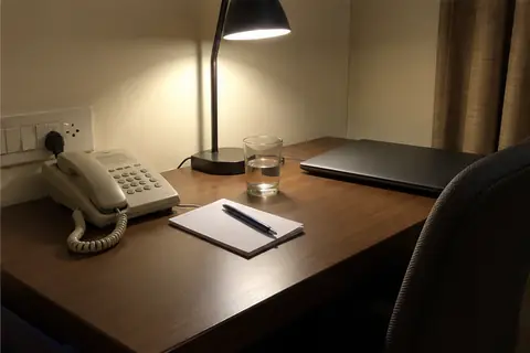 A hotel room desk at night with the intercom phone and a blank notepad