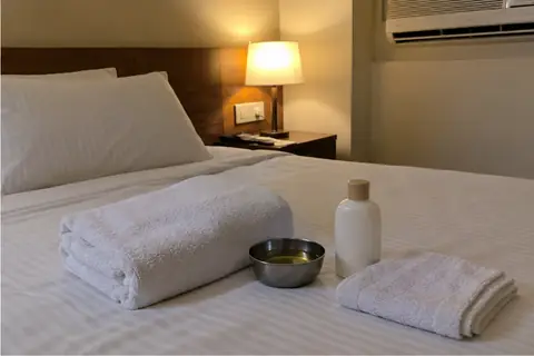 Towels and a bowl of warm oil on a hotel bed in Pune