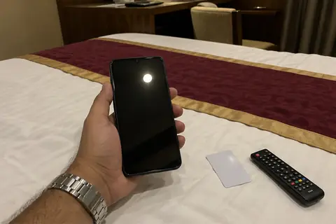 A man holds his phone over a hotel bed in Pune, ready to send a message