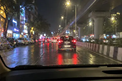 A Pune road at night seen from a cab, wet after rain