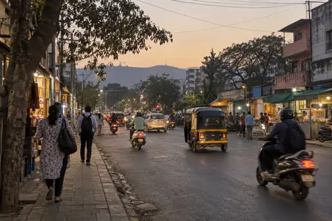 A Pune street at dusk, people walking home and an auto-rickshaw